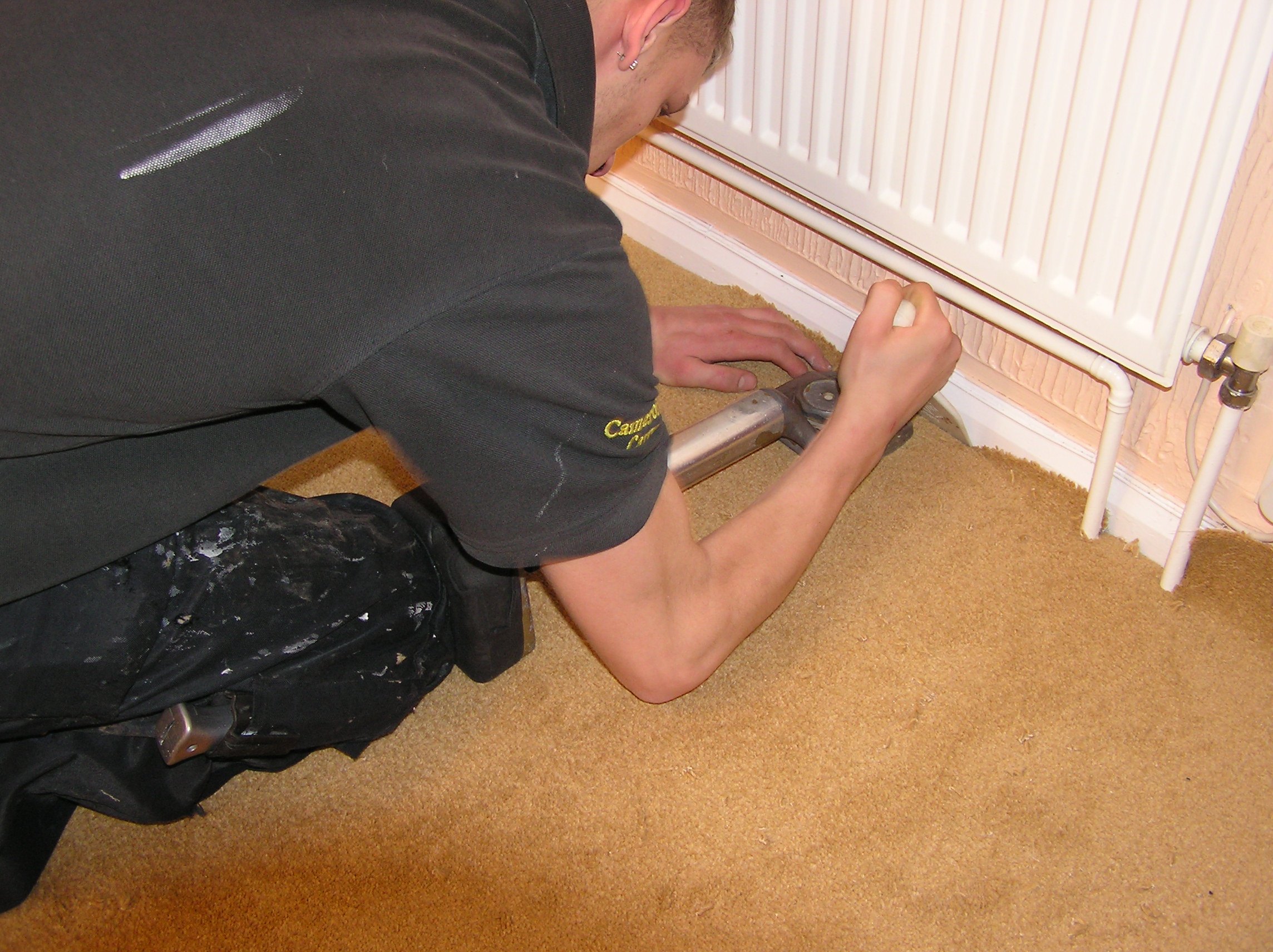 Flooring worker stretching carpet into place during installation